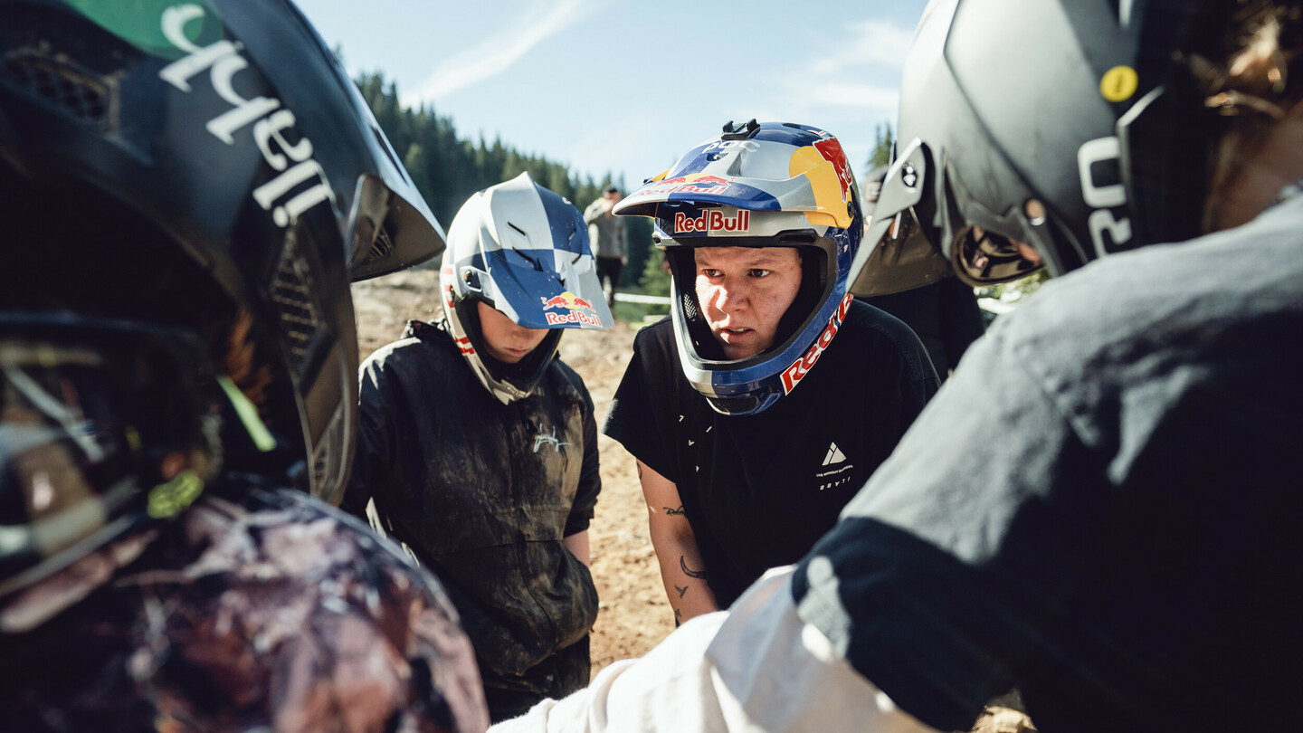 Un groupe de cyclistes de montagne, tous portant des casques, réunis en discussion. Ils portent divers casques, et sont en tenue sportive.